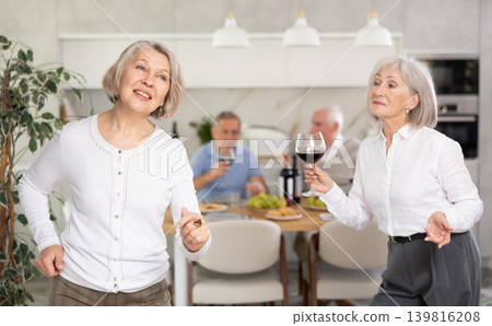 Senior men and women have fun dancing during house party. Senior men and women have fun dancing during house party. 139816208