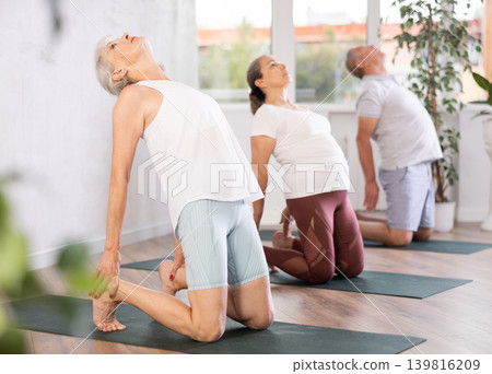 Elderly women doing body stretching in yoga class Elderly women doing body stretching in yoga class 139816209