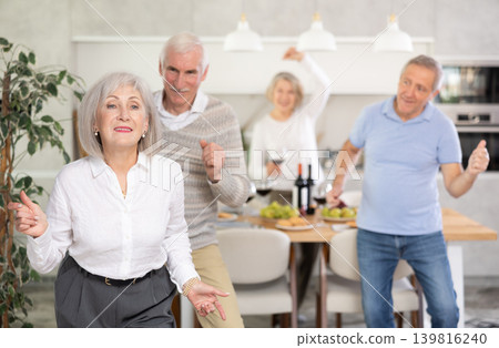 Senior men and women have fun dancing during house party. Senior men and women have fun dancing during house party. 139816240