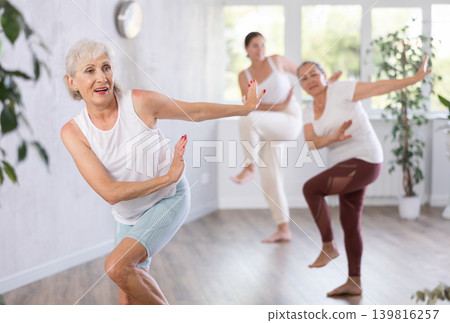 Group of mature sports women and man in activewear exercising dynamic dancing movemens in modern gym studio Group of mature sports women and man in activewear exercising dynamic dancing movemens in modern gym studio 139816257