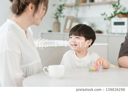 A boy and his family eating snacks in the living room. 139816298
