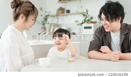 A boy and his family eating snacks in the living room. 139816299