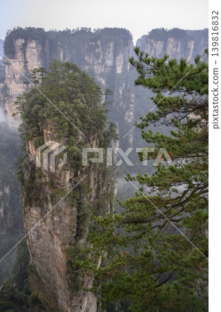Pillars of the Tianmenshan Mountains rising from the jungle in the fog near Zhangjiajie, China 139816832
