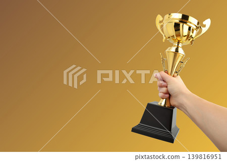 Hand holding a golden trophy with a black base Hand holding a golden trophy with a black base 139816951