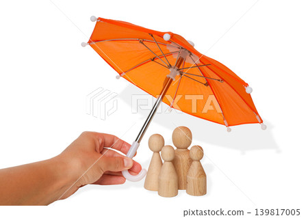A hand holds an orange umbrella over wooden figures, isolated, PNG A hand holds an orange umbrella over wooden figures, isolated, PNG 139817005
