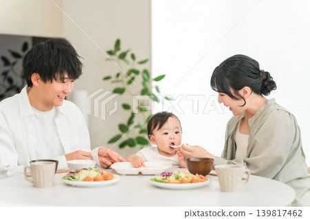 Mother and father feeding baby food at the dinner table (childcare and parenting) Mother and father feeding baby food at the dinner table (childcare and parenting) 139817462