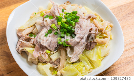平底鍋裡盛著蒸好的豬肉和高麗菜,放在木桌上。 平底鍋裡盛著蒸好的豬肉和高麗菜,放在木桌上。 139817485