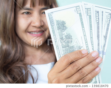 Woman holding cash 100 dollar she smile and happy, cash for bus shopping on black fridays, concept for business investment income, credit success, earning or salary Woman holding cash 100 dollar she smile and happy, cash for bus shopping on black fridays, concept for business investment income, credit success, earning or salary 139818470