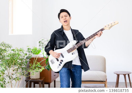 A man whose hobby is playing musical instruments, specifically the bass guitar. A man whose hobby is playing musical instruments, specifically the bass guitar. 139818735