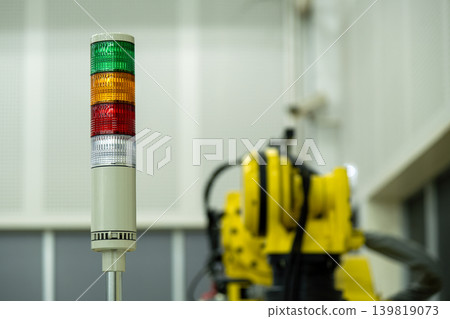 Industrial signal tower light with green, yellow and red indicators beside robotic automation system in smart factory environment, representing manufacturing safety and machine status monitoring Industrial signal tower light with green, yellow and red indicators beside robotic automation system in smart factory environment, representing manufacturing safety and machine status monitoring 139819073
