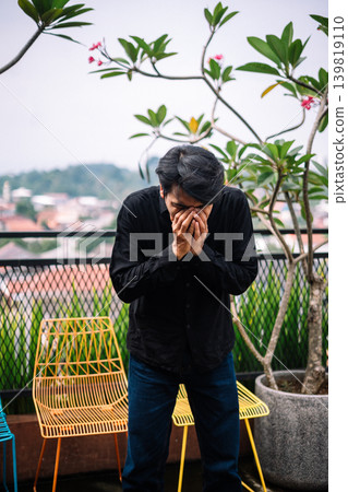 Asian man sneezing outdoors with cold and allergy concept Asian man sneezing outdoors with cold and allergy concept 139819110