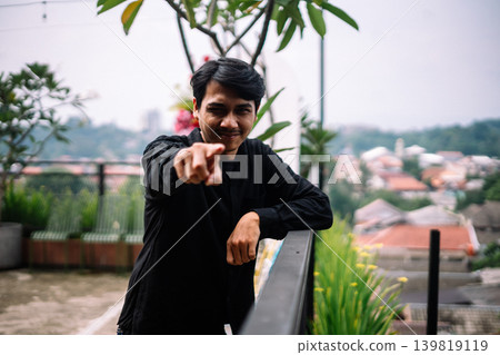 Southeast Asian man pointing toward camera outdoors 139819119