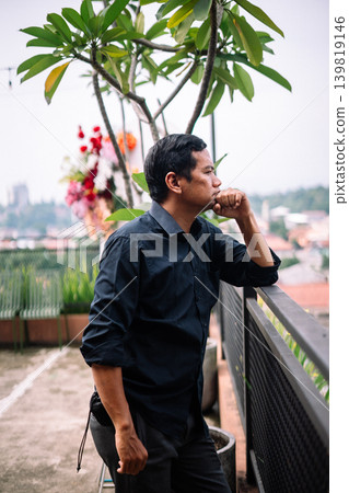 Pensive Man Looking Out Over Urban Landscape from Balcony Pensive Man Looking Out Over Urban Landscape from Balcony 139819146
