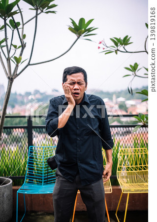 Adult Man Suffering from Severe Toothache Outdoors on a Balcony Adult Man Suffering from Severe Toothache Outdoors on a Balcony 139819168