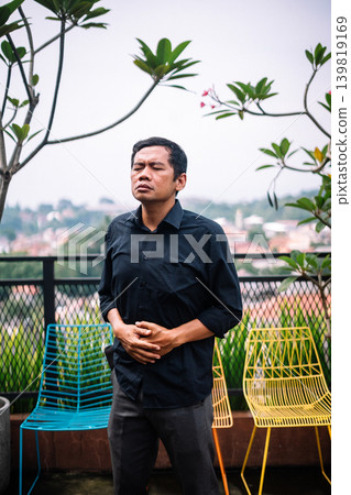 Man Suffering from Abdominal Pain on Outdoor Balcony 139819169