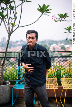 Man Suffering From Stomach Pain and Discomfort Outdoors 139819170
