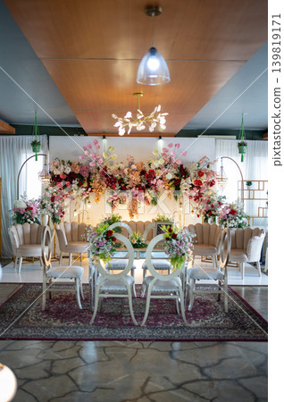 Elegant wedding stage decoration with akad table and beautiful floral backdrop at luxury indoor venue Elegant wedding stage decoration with akad table and beautiful floral backdrop at luxury indoor venue 139819171