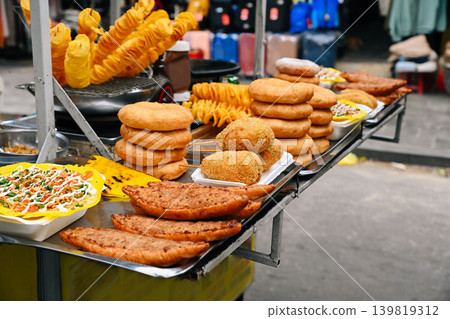 An abundance of traditional Vietnamese street food snacks including corn dogs donuts and banh mi are displayed at a market stall in Hoi An Vietnam An abundance of traditional Vietnamese street food snacks including corn dogs donuts and banh mi are displayed at a market stall in Hoi An Vietnam 139819312