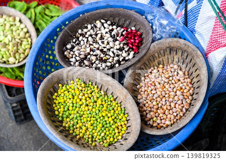 A variety of colorful fresh beans and peas are displayed in plastic baskets at a traditional outdoor street market stall in Hoi An Vietnam A variety of colorful fresh beans and peas are displayed in plastic baskets at a traditional outdoor street market stall in Hoi An Vietnam 139819325