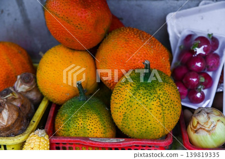 A close up view of exotic fresh qua gac or gac fruits inside a red plastic basket at a traditional street fruit market stall in Hoi An Vietnam A close up view of exotic fresh qua gac or gac fruits inside a red plastic basket at a traditional street fruit market stall in Hoi An Vietnam 139819335