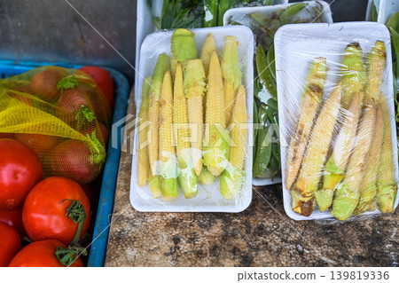 Fresh raw bap bao tu baby corn cobs in plastic wrap displayed at a traditional street vegetable market stall in Hoi An ancient town Vietnam Fresh raw bap bao tu baby corn cobs in plastic wrap displayed at a traditional street vegetable market stall in Hoi An ancient town Vietnam 139819336