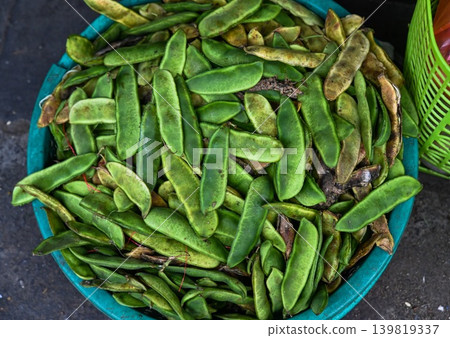 A close up top view of fresh raw green dau ngu lima bean pods displayed inside a plastic container at a traditional street market in Vietnam A close up top view of fresh raw green dau ngu lima bean pods displayed inside a plastic container at a traditional street market in Vietnam 139819337