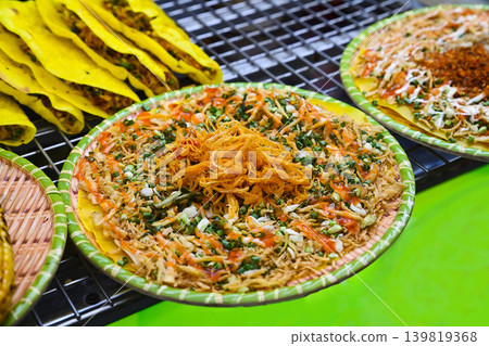 Traditional crispy Vietnamese rice paper pizza banh trang nuong with bright toppings on tray at outdoor street food market stall in Vietnam Traditional crispy Vietnamese rice paper pizza banh trang nuong with bright toppings on tray at outdoor street food market stall in Vietnam 139819368