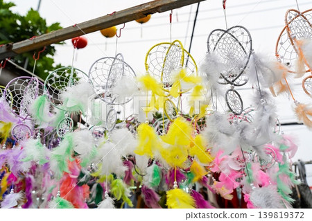 Colorful handmade dreamcatchers with soft feathers hanging for sale at traditional outdoor street souvenir market booth in Vietnam 139819372