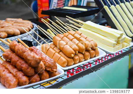 Traditional Vietnamese street food skewers featuring sausages meatballs and cheese blocks displayed at outdoor night market stall in Vietnam Traditional Vietnamese street food skewers featuring sausages meatballs and cheese blocks displayed at outdoor night market stall in Vietnam 139819377