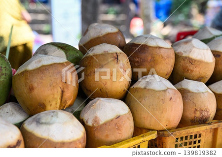 Fresh peeled young orange coconuts stacked inside plastic crates for sale at traditional outdoor street market place in Vietnam Fresh peeled young orange coconuts stacked inside plastic crates for sale at traditional outdoor street market place in Vietnam 139819382