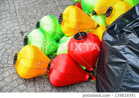 A pile of colorful traditional Vietnamese silk lanterns lies on the ground prepared for decoration or sale in Hoi An Quang Nam province Vietnam A pile of colorful traditional Vietnamese silk lanterns lies on the ground prepared for decoration or sale in Hoi An Quang Nam province Vietnam 139819391