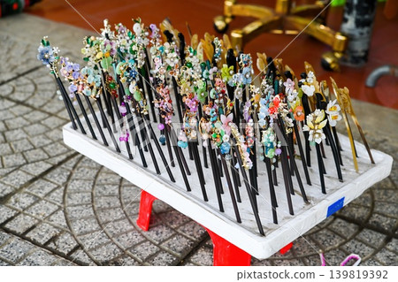 Traditional elegant handmade hairpins decorated with colorful floral ornaments displayed at outdoor souvenir street market booth in Hoi An Vietnam Traditional elegant handmade hairpins decorated with colorful floral ornaments displayed at outdoor souvenir street market booth in Hoi An Vietnam 139819392