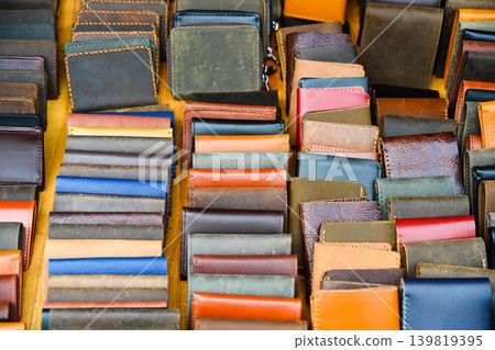Many handmade leather wallets and cardholders of various colors displayed in rows for sale at outdoor souvenir market in Hoi An Vietnam Many handmade leather wallets and cardholders of various colors displayed in rows for sale at outdoor souvenir market in Hoi An Vietnam 139819395