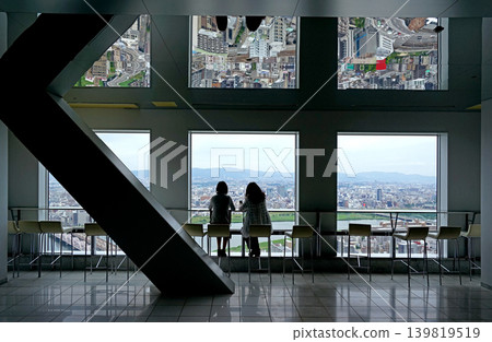 Two people enjoying panoramic Japan Osaka city view from high rise observation deck with mirrored ceiling Two people enjoying panoramic Japan Osaka city view from high rise observation deck with mirrored ceiling 139819519
