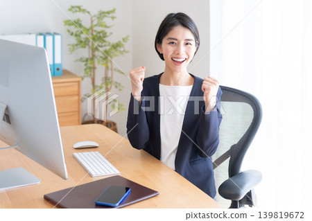 A businesswoman working on her desktop computer (making a victory pose) 139819672