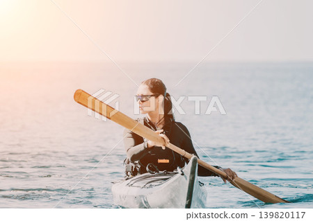 Woman Kayaking Ocean Paddle Sunrise: Solo Kayaking on the ocean at sunrise, a woman paddles her kayak towards the sun. Woman Kayaking Ocean Paddle Sunrise: Solo Kayaking on the ocean at sunrise, a woman paddles her kayak towards the sun. 139820117
