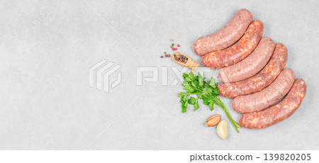 Raw sausages with parsley and garlic on gray background top view Raw sausages with parsley and garlic on gray background top view 139820205