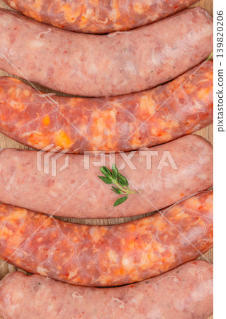 Raw sausages background on wooden surface close up 139820206