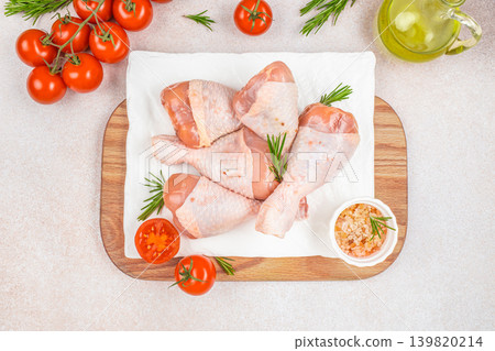 Raw chicken drumsticks with tomatoes and rosemary on cutting board top view Raw chicken drumsticks with tomatoes and rosemary on cutting board top view 139820214