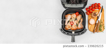 Air fryer chicken drumsticks with spices and tomatoes, top view healthy cooking background with copy space 139820215