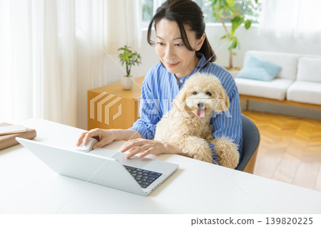 Telework: A middle-aged woman working while holding a dog 139820225