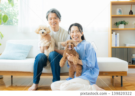 一對中年夫婦在客廳和他們的狗一起玩耍 139820322