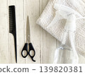 Hairdressing tools for haircuts at a beauty salon: hair scissors and comb with a wood grain background, spray bottle, hair salon treatments, and styling tools set. 139820381