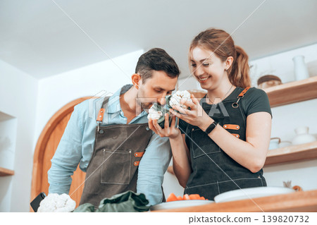 Happy couple cooking healthy food together in a modern kitchen Happy couple cooking healthy food together in a modern kitchen 139820732