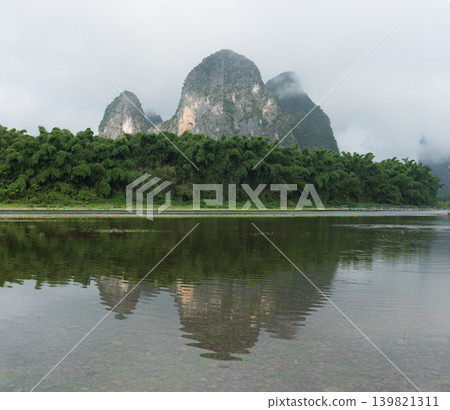 The beautiful inverted reflections of the karst peaks and the ink-painting-like scenery are visible on the calm surface of the Li River. The beautiful inverted reflections of the karst peaks and the ink-painting-like scenery are visible on the calm surface of the Li River. 139821311