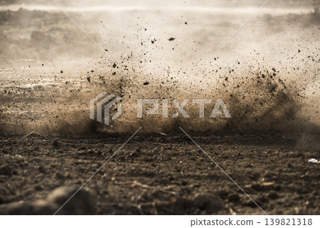 A dynamic moment of mud and dust flying violently from the ground. 139821318
