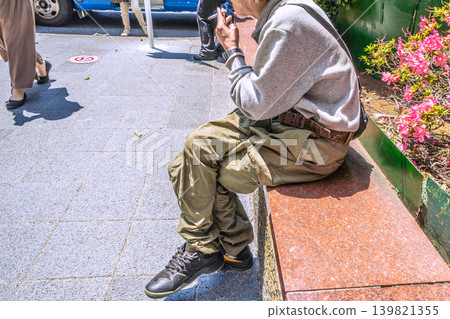 一位老人在橫濱站西出口吸煙,這是日本橫濱市的城市景觀。不知何故,橫濱站附近老年人吸煙的現象急劇增加… 一位老人在橫濱站西出口吸煙,這是日本橫濱市的城市景觀。不知何故,橫濱站附近老年人吸煙的現象急劇增加… 139821355