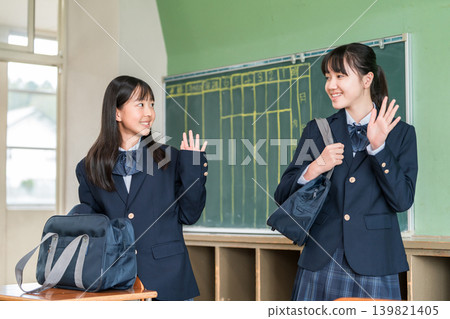 Smiling middle school and high school girls greeting friends in a school classroom as they go to school. Smiling middle school and high school girls greeting friends in a school classroom as they go to school. 139821405