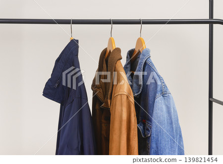 Different men jackets hanging on clothing rack. Garments include leather textile and denim pieces. Menswear outerwear assortment for casual wardrobe.. Different men jackets hanging on clothing rack. Garments include leather textile and denim pieces. Menswear outerwear assortment for casual wardrobe.. 139821454