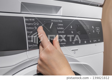 Setting and choosing laundry program on washing machine panel. 139821812